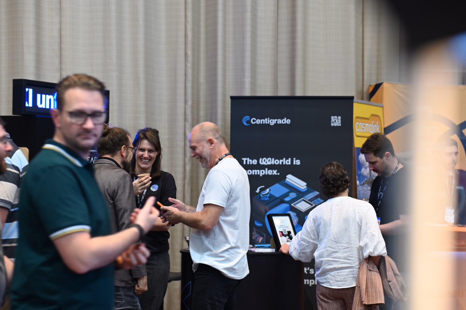 Visitors chatting at the Centigrade booth at IT.CON, with a Centigrade banner and a tablet in the background.