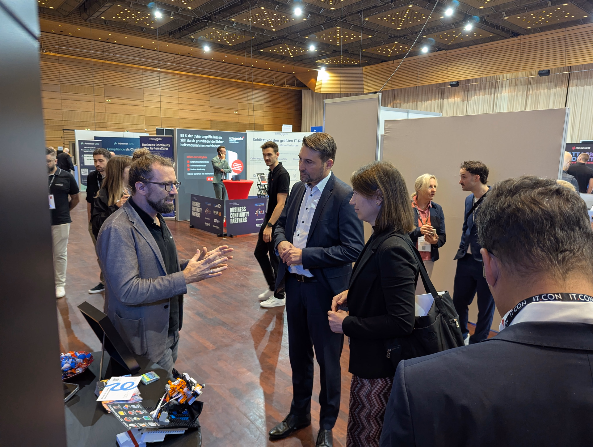 A conversation with a group of visitors at the Centigrade booth in the Saarlandhalle; information materials and a robot model sit on the table.